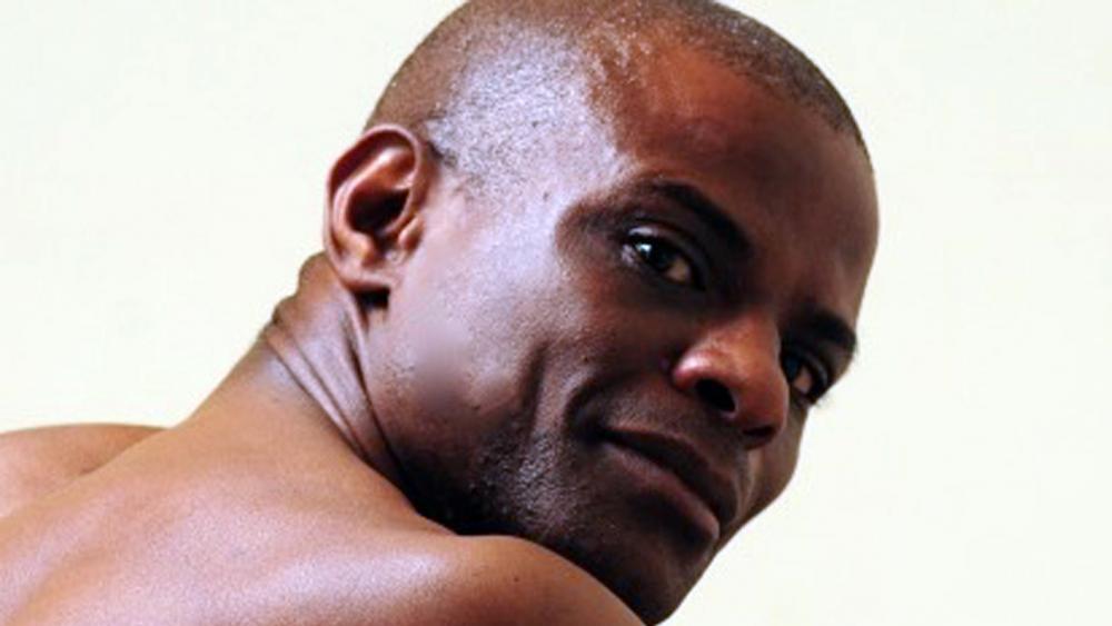 A black man is looking over his shoulder a the camera for a headshot.