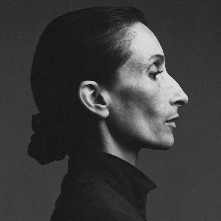 A headshot sized photo in black and white. The woman is wearing a black turtle neck sweater and has a solemn face.