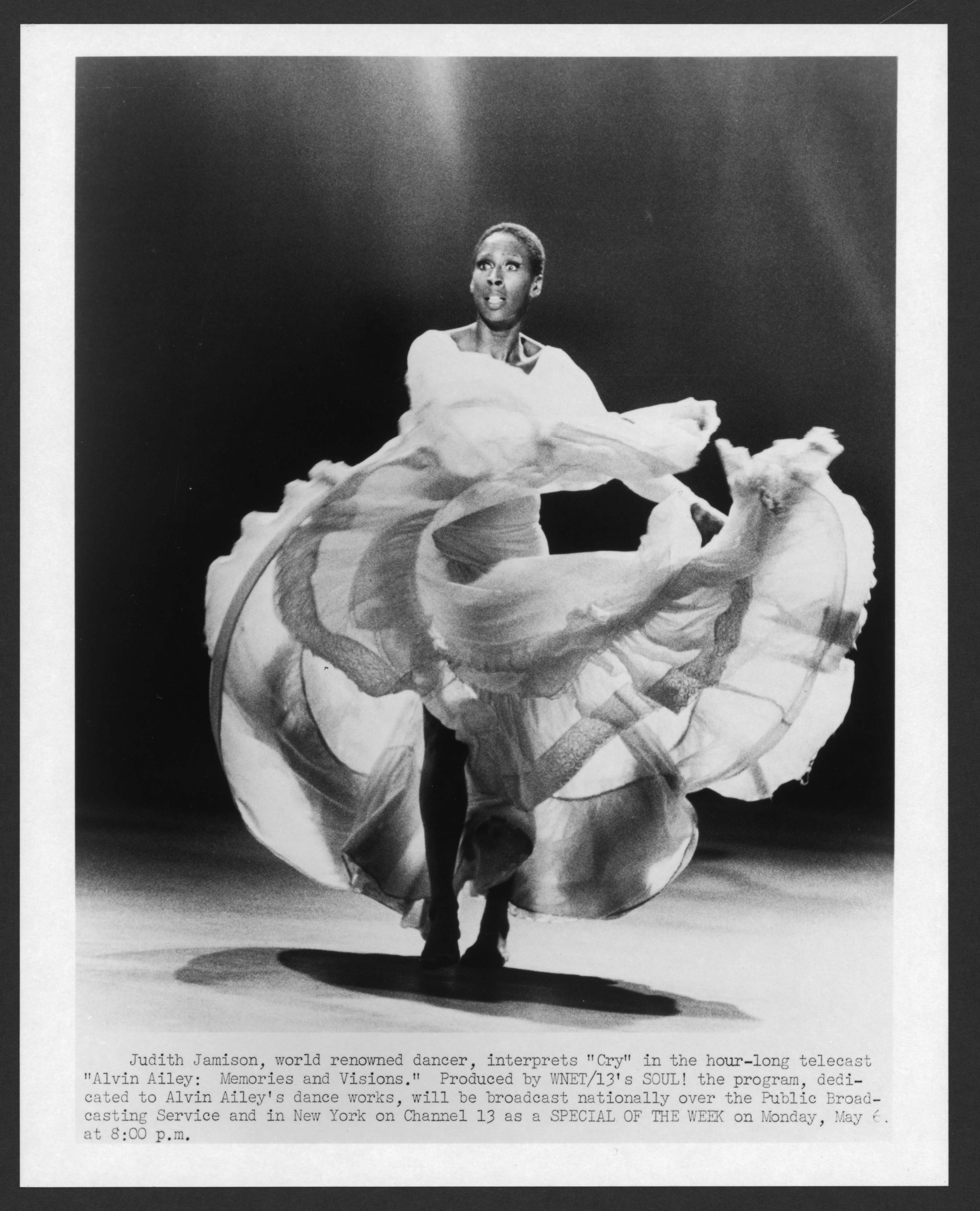 Black and white photo of a woman dancing in a white dress.