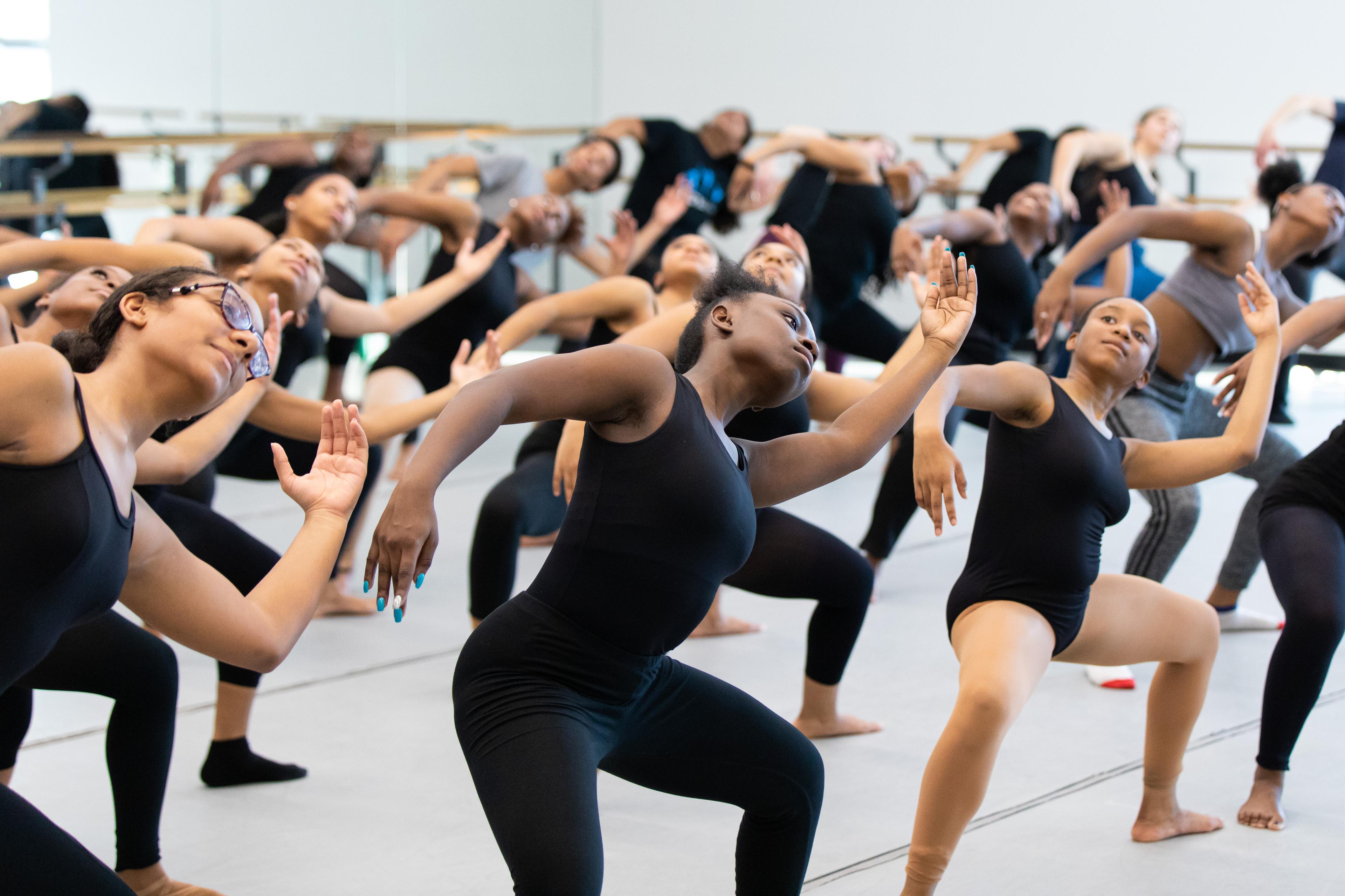 Dance students performing modern choreography in a deep second position leaning to the side