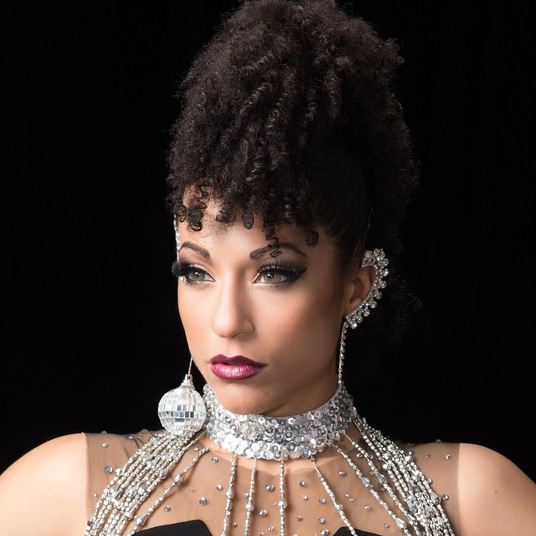 Princess Lockerooo wearing a sparkly top and a disco ball earring with her hair pulled up