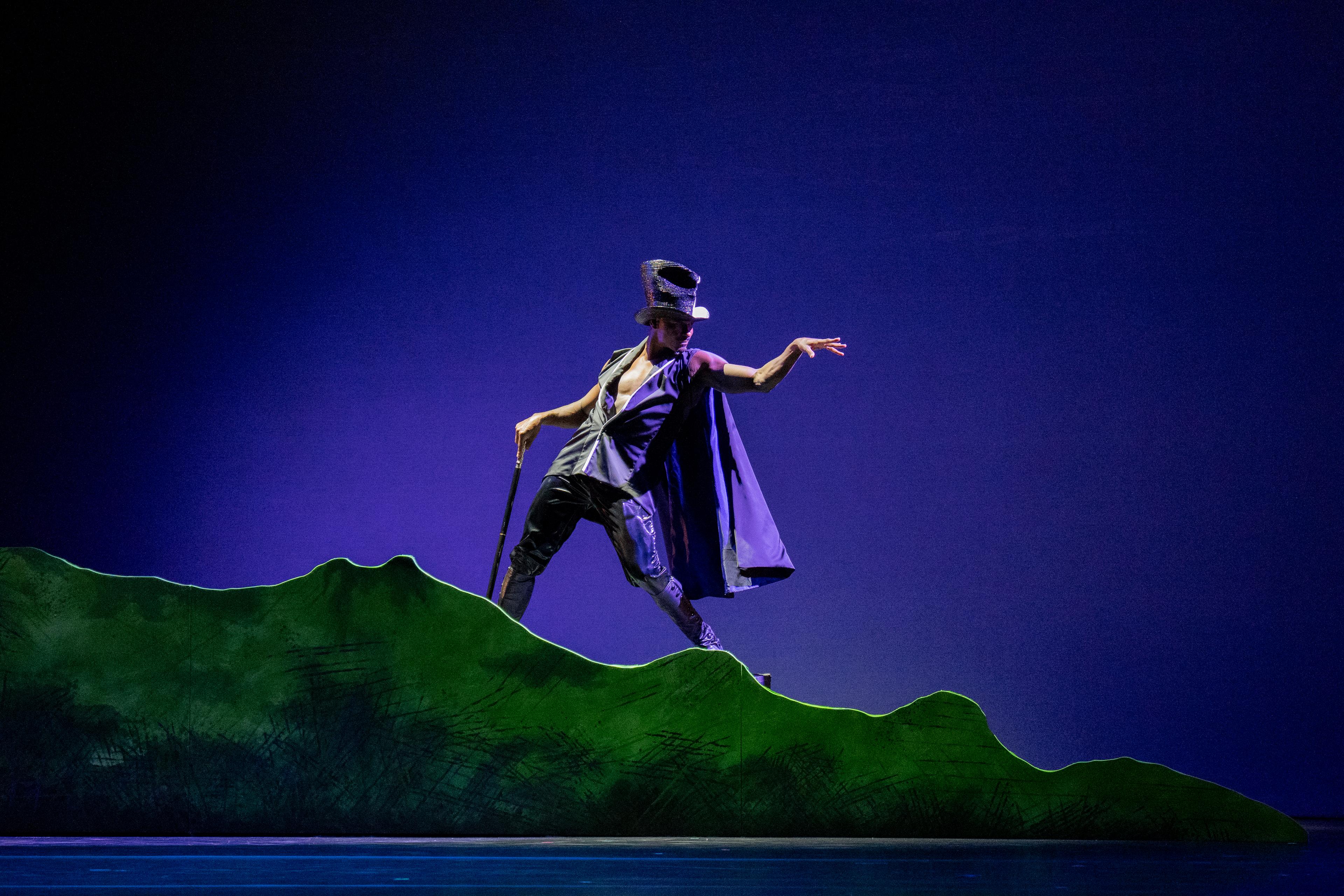 Male dancer wearing purple cape and top hat