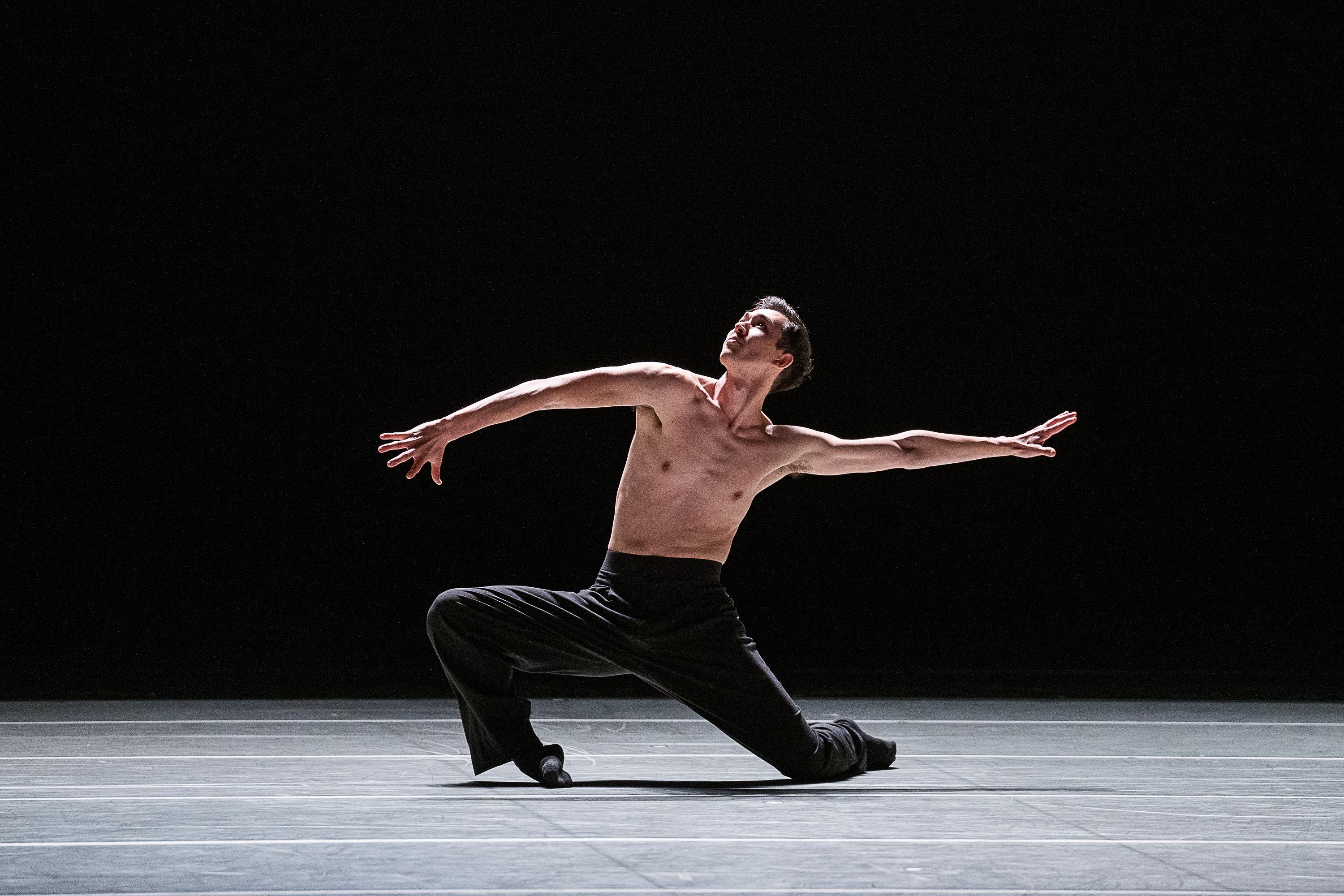 Male dancer wearing black pants lunging to his knees