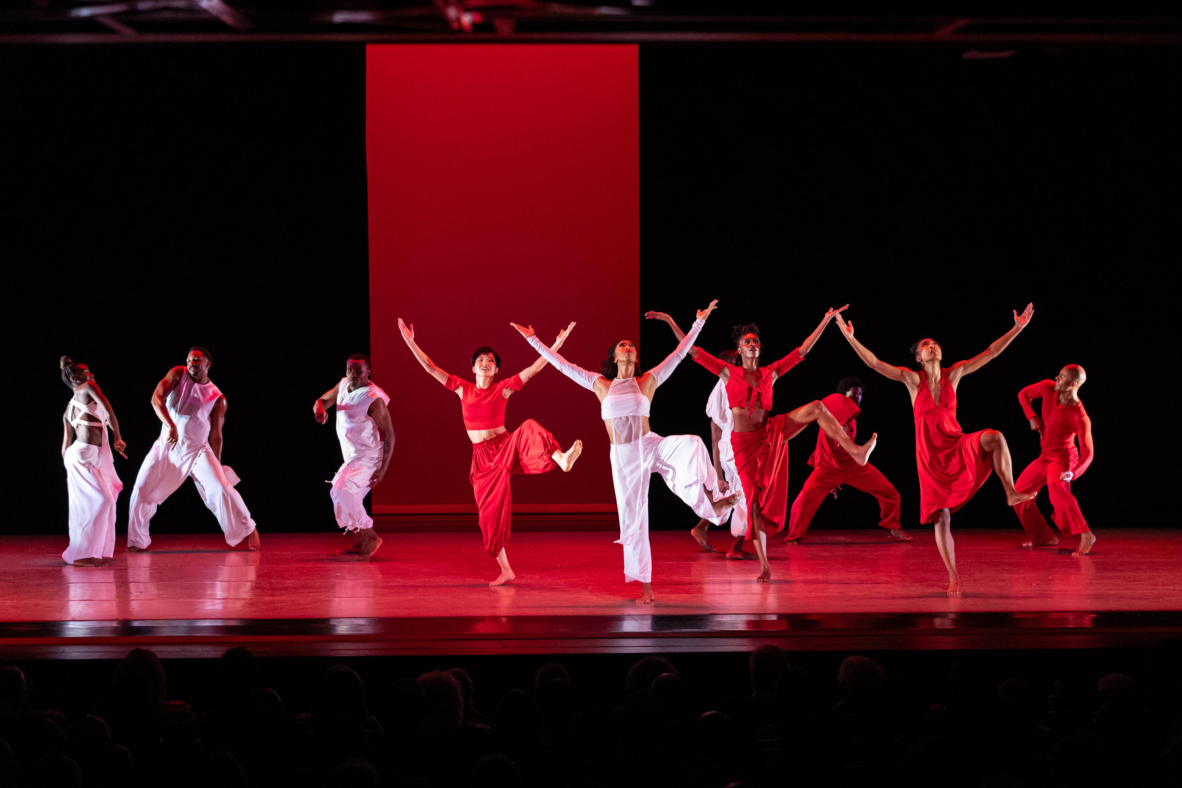 Group of dancers wearing red and white with their arms extended
