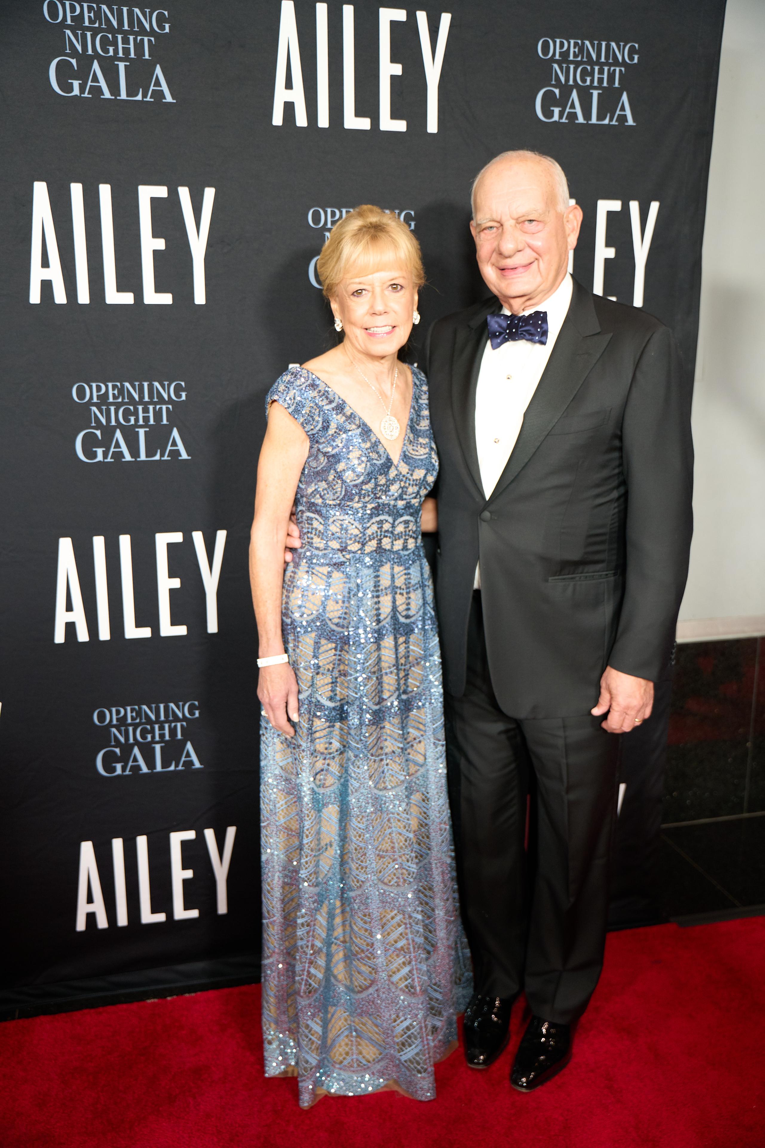 A woman in a silver evening gown stands next to a man in a black suit.