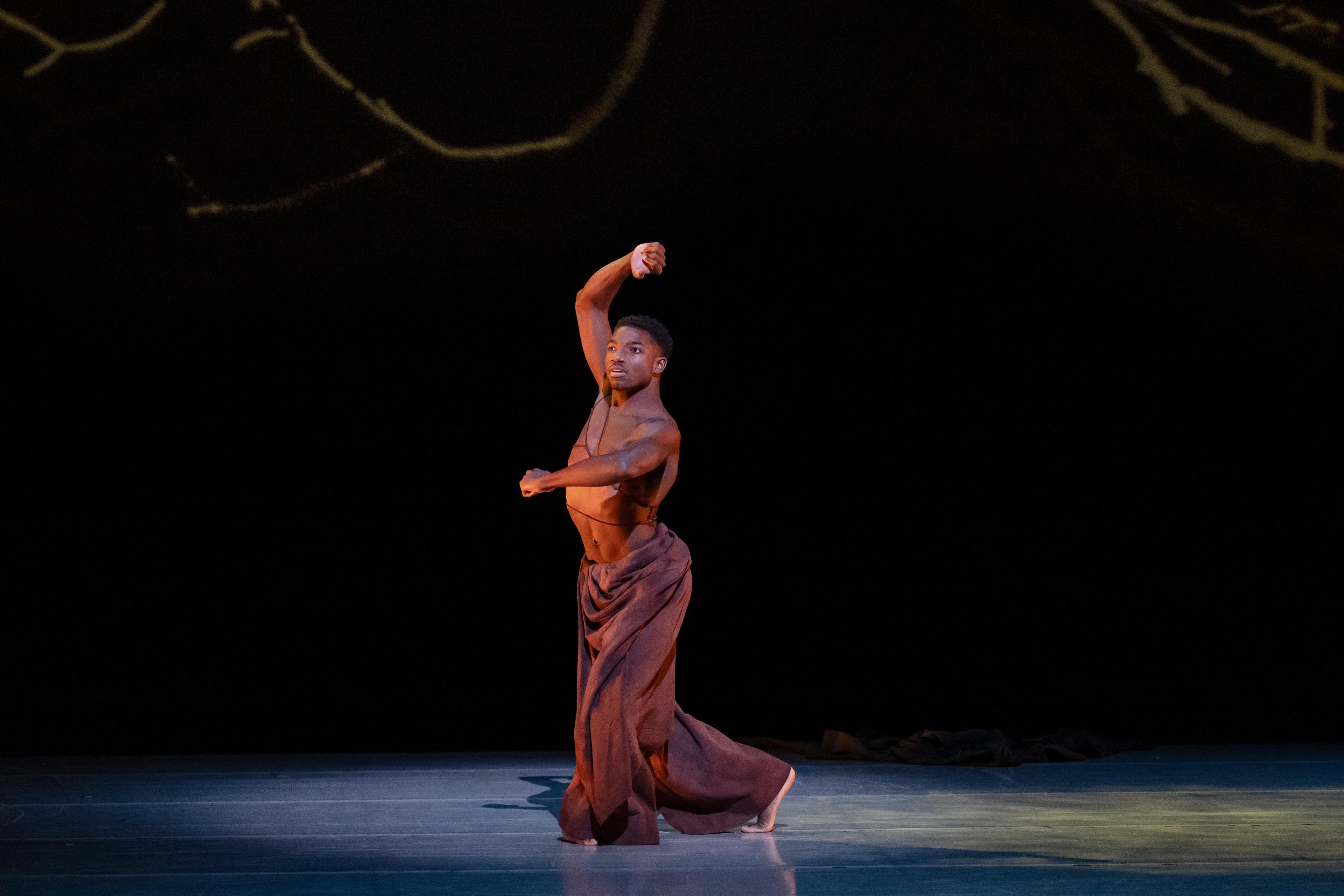 Male dancer wearing brown pants in the spotlight