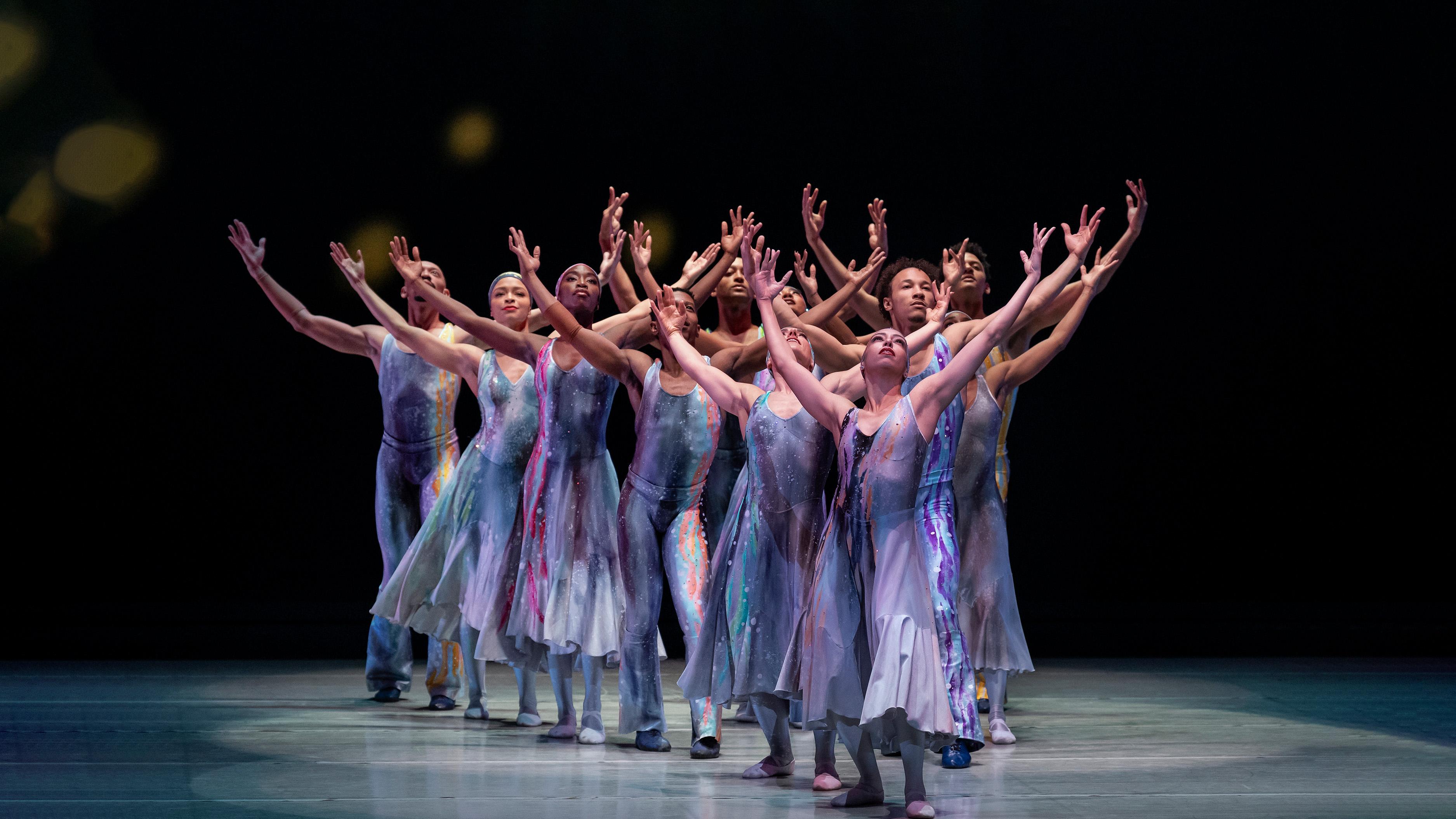 Dancers in low lighting with arms outstretched