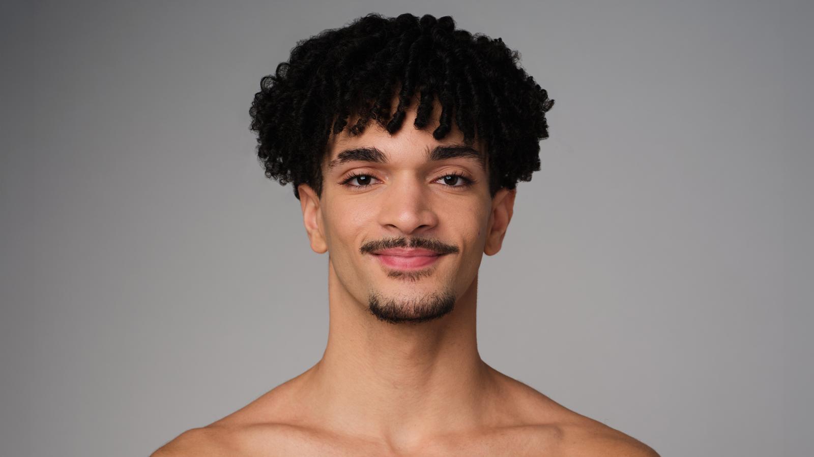 Headshot of Alvin Ailey American Dance Theater dancer Michael Cherry, he has facial hair and curly hair