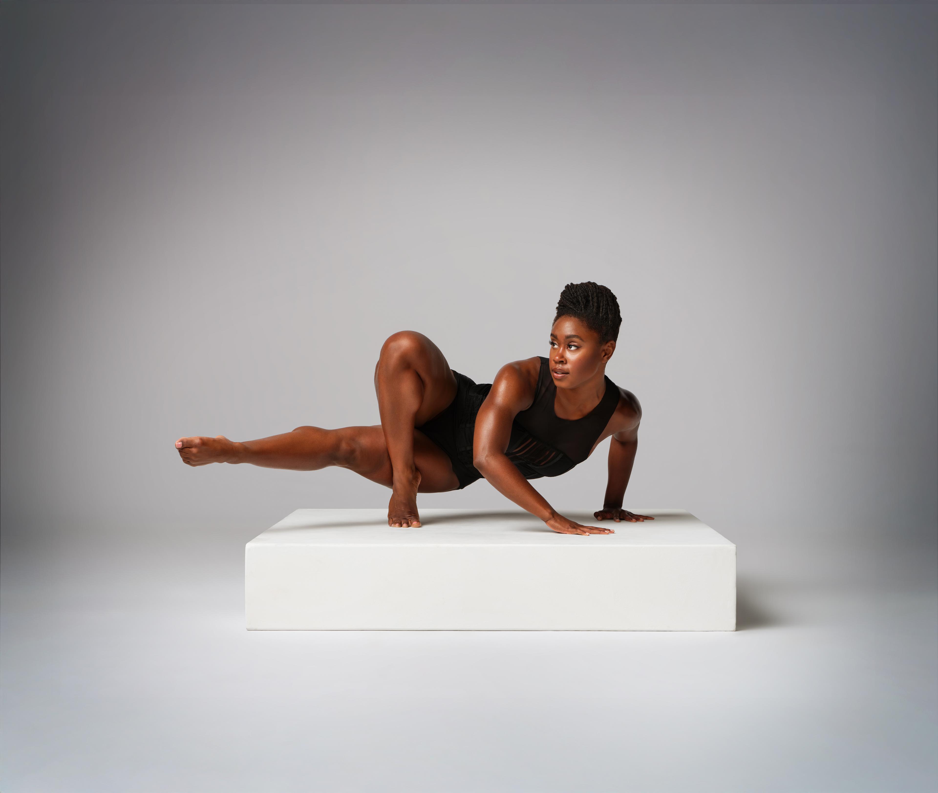 Ashley Kaylynn Green in black leotard posing on white platform