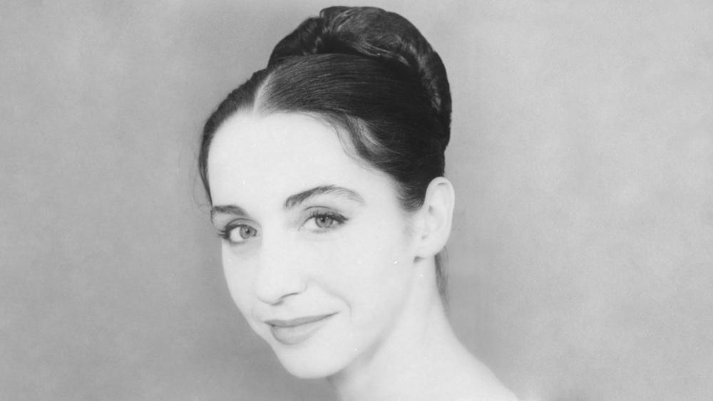 A black and white head shot of a woman. She has a bun.