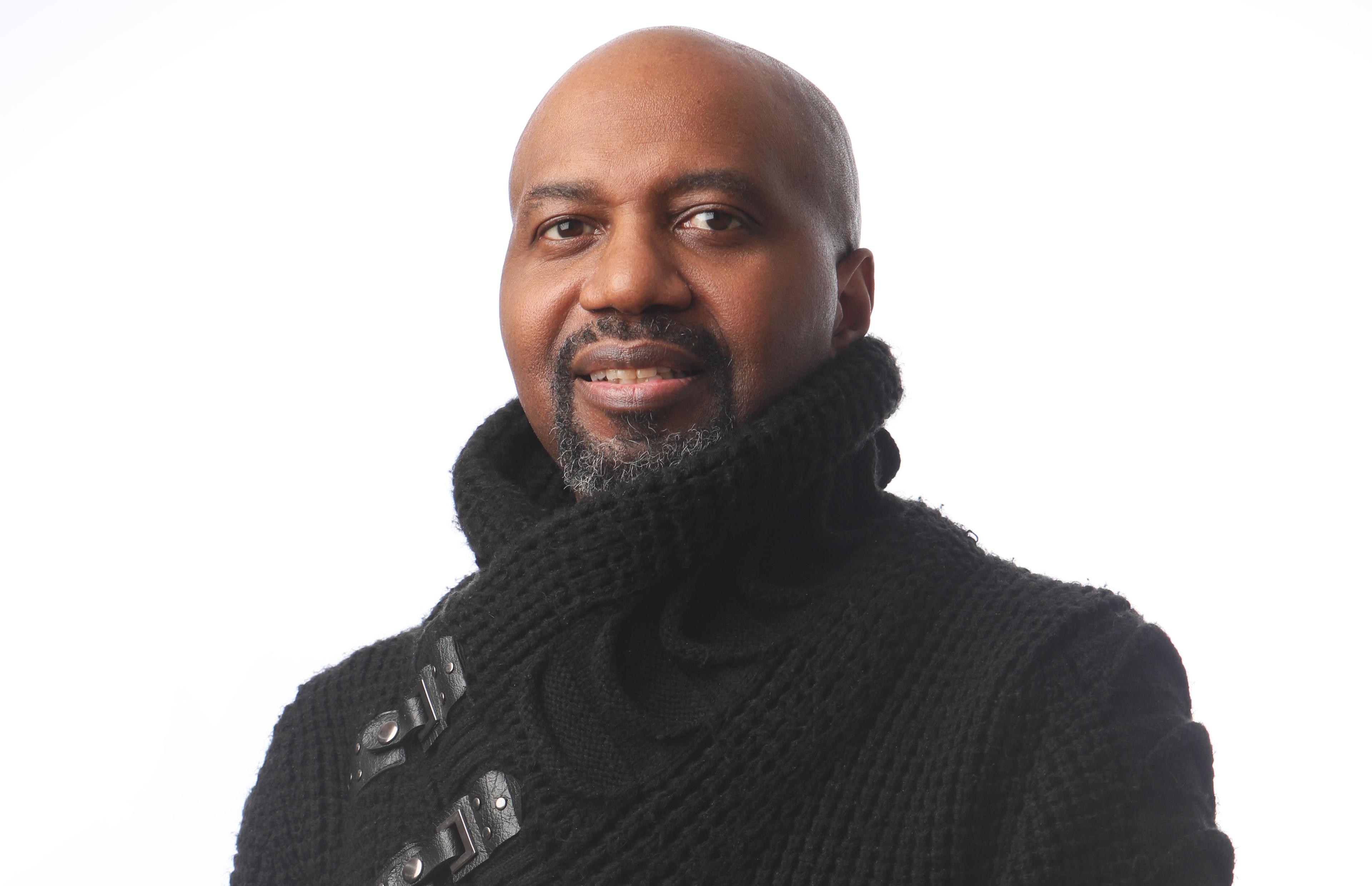 portrait of a bald black man wearing a chunky black sweater