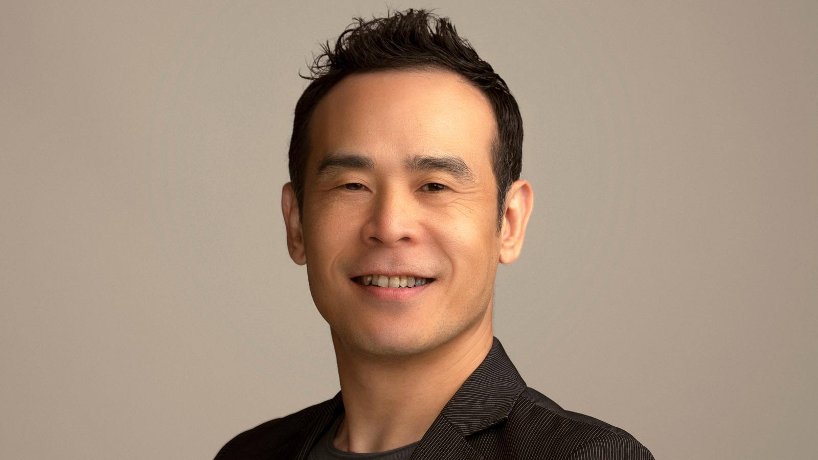 A headshot of Kanji Segawa. A man with dark short hair and a slight smile