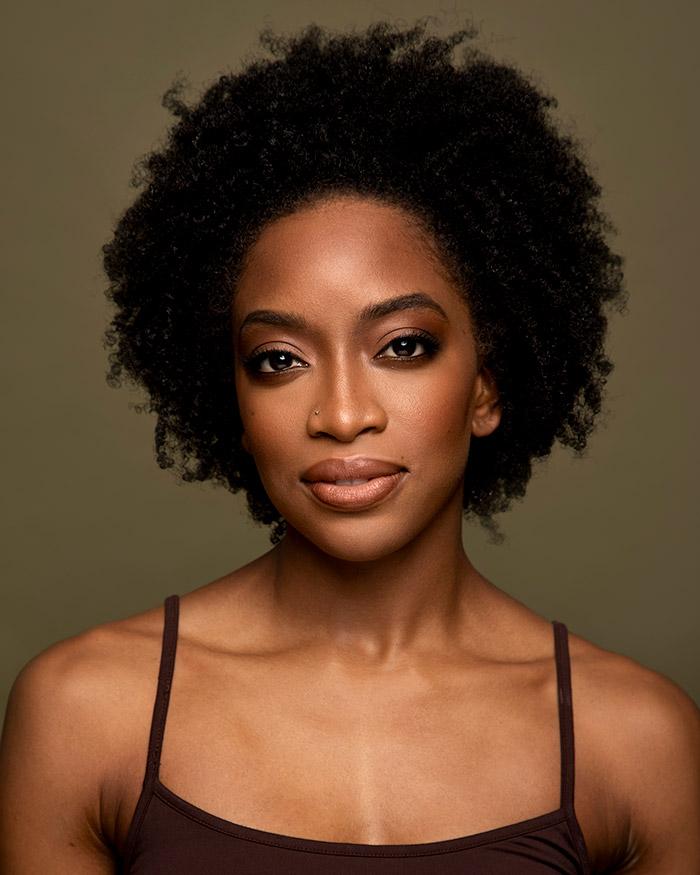Tamisha A Guy in a black tank top against a dark green background